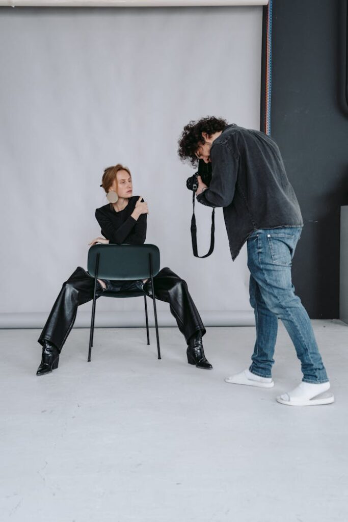 Man in Black Long Sleeve Shirt and Blue Denim Jeans Sitting on Black Chair